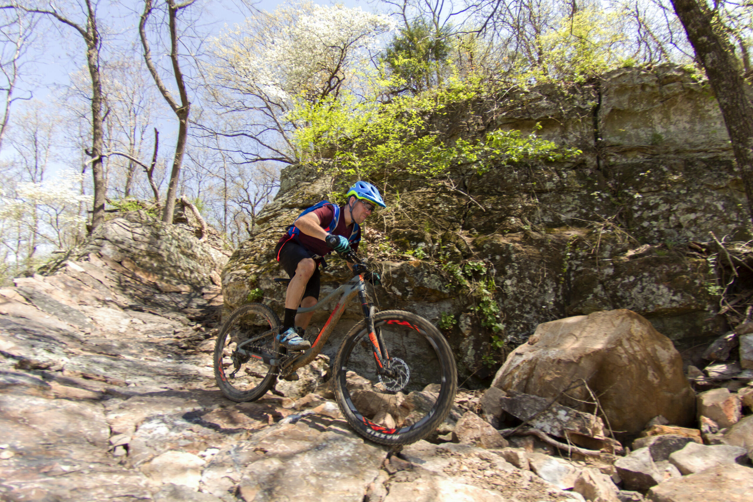 A mountain biker riding his bike down the large brown stone hill of Thunder Chicken Trailhead.